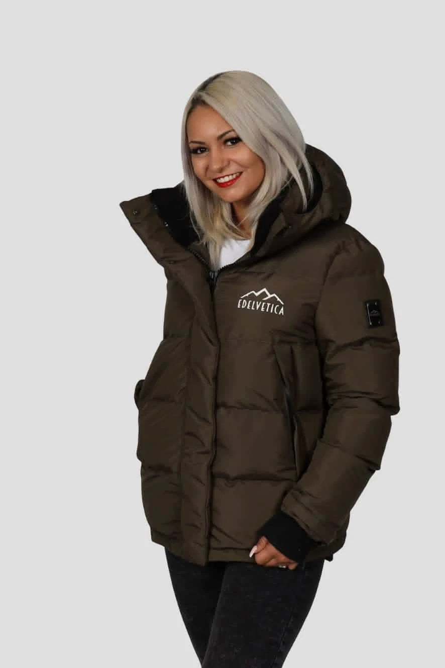 Damen Winterjacke von Edelvetica, handgefertigt für höchste Qualität. Diese stilvolle Jacke zeichnet sich durch ein einzigartiges Edelweiss-Muster auf der Innenseite aus, das traditionelle Schweizer Elemente mit modernem Design verbindet. Die Jacke verbindet Funktionalität mit einem stilvollen Design, ideal für den modischen Auftritt in der Winterlandschaft.