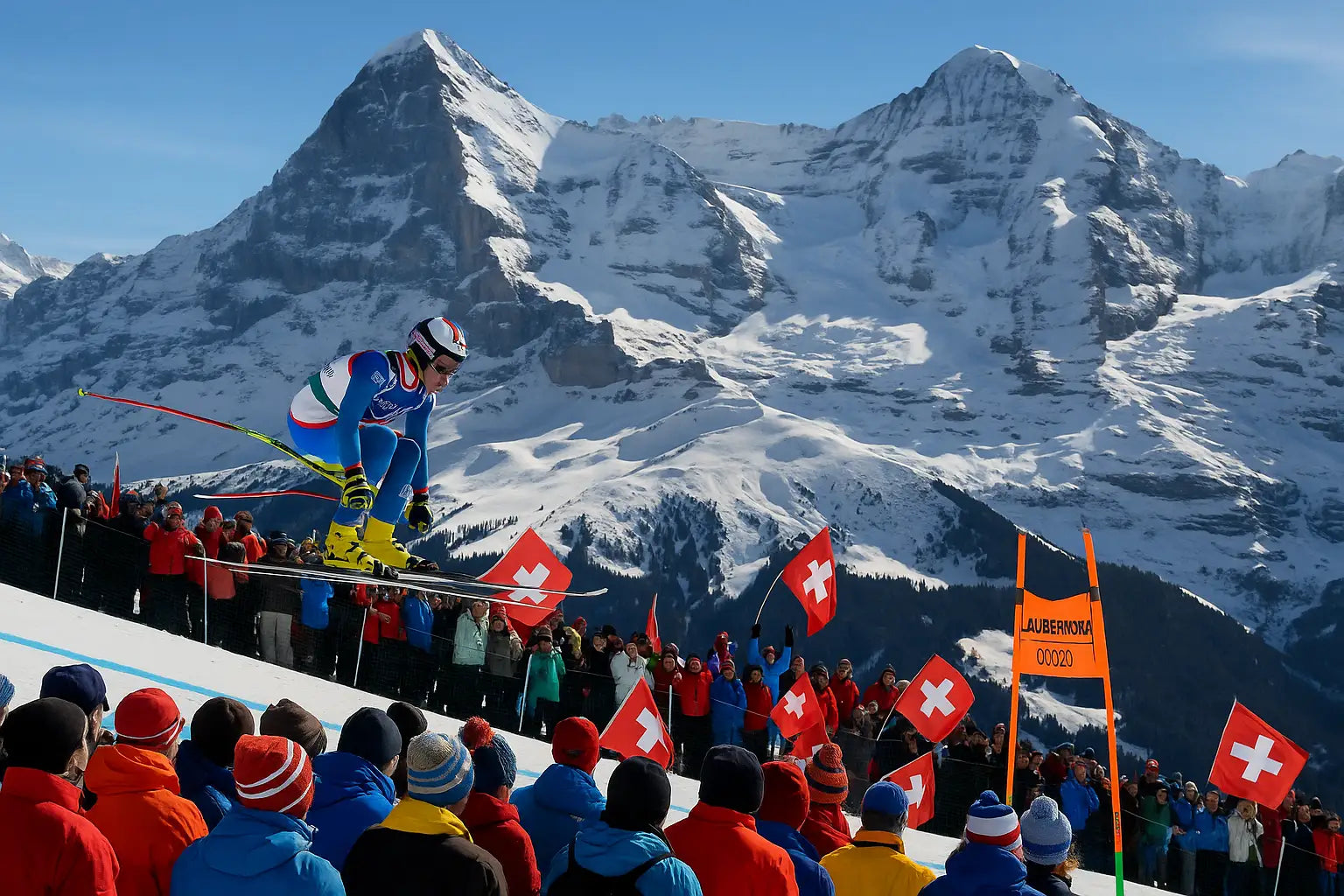 Skirennfahrer springen dynamisch am legendären Hundschopf-Sprung der Lauberhornabfahrt.