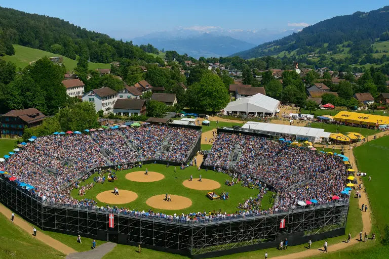 Ein Traditionelles Schwingfest in der Schweiz in einer großen Arena während mehrere Schwingkämpfe vollzogen werden.
