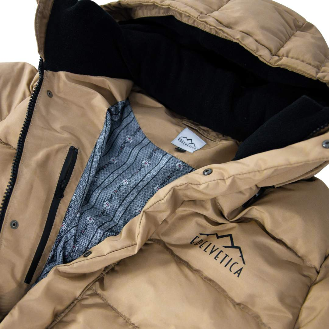 Damen Winterjacke von Edelvetica, handgefertigt für höchste Qualität. Diese stilvolle Jacke zeichnet sich durch ein einzigartiges Edelweiss-Muster auf der Innenseite aus, das traditionelle Schweizer Elemente mit modernem Design verbindet. Die Jacke verbindet Funktionalität mit einem stilvollen Design, ideal für den modischen Auftritt in der Winterlandschaft.